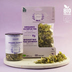 Organic Olympus Tea Relax packaging and loose tea on a white surface with a purple background