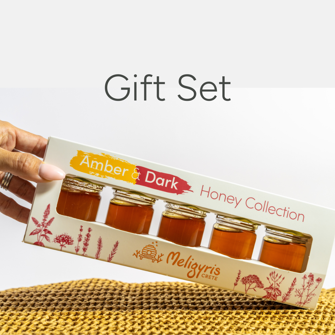 Gift set of Amber & Dark Honey Collection by Meligyris Crete held by a hand on a white background.