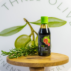 Bottle of Fig Balsamic cream on a wooden stand with green leaves in the background