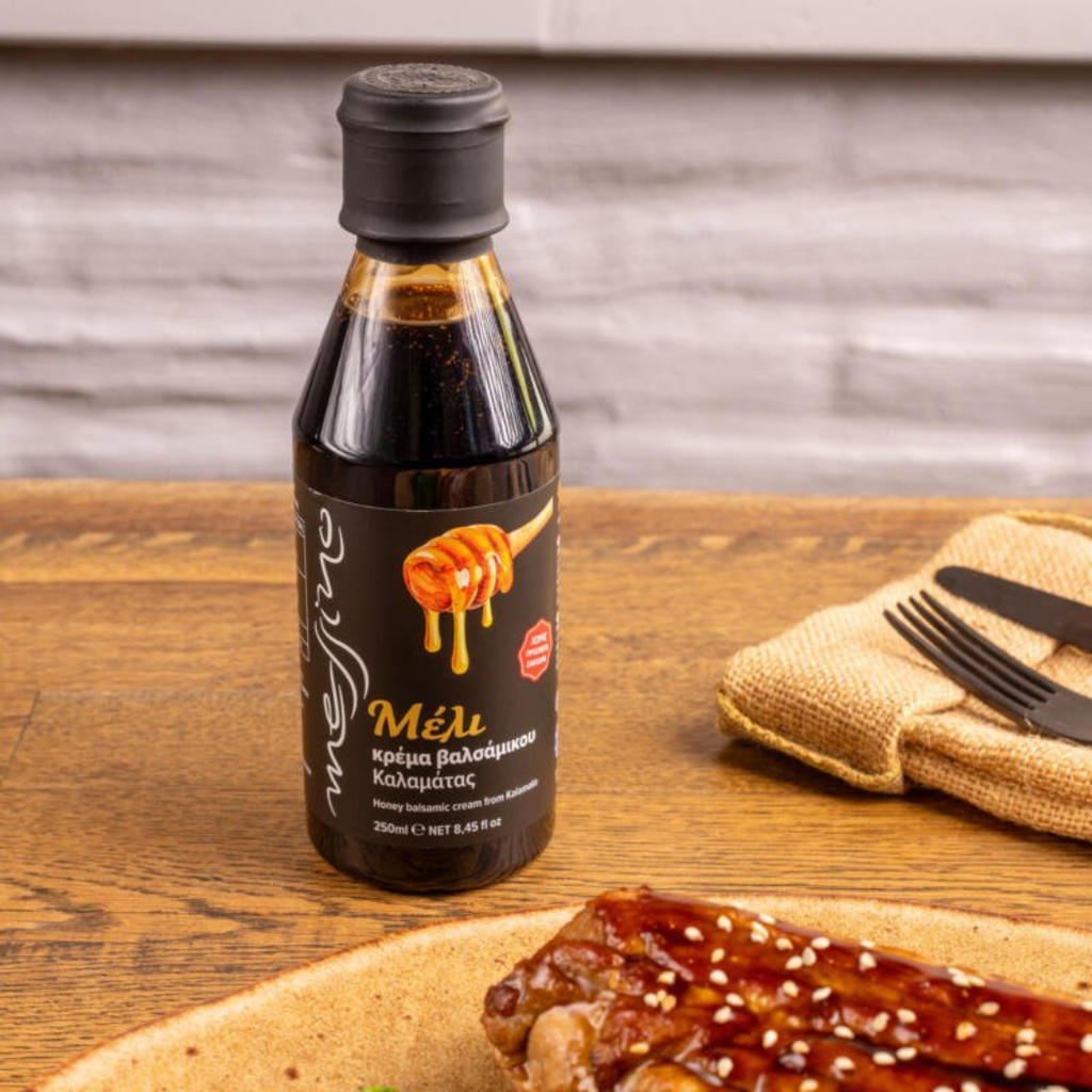 Bottle of honey on a wooden table with food and cutlery in the background