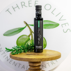 Bottle of Three Olives Organic Balsamicio on a wooden stand with green olives and rosemary.