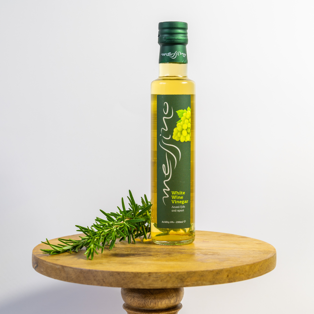 Bottle of white wine vinegar with a green label on a wooden stand against a white background