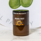Jar of Organic Forest Honey with a decorative plate in the background