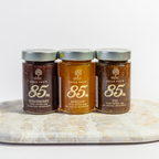 Three jars of jam on a marble surface with a white background
