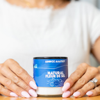 Person holding a container labeled 'Natural Fleur de Sel' with a blue label.