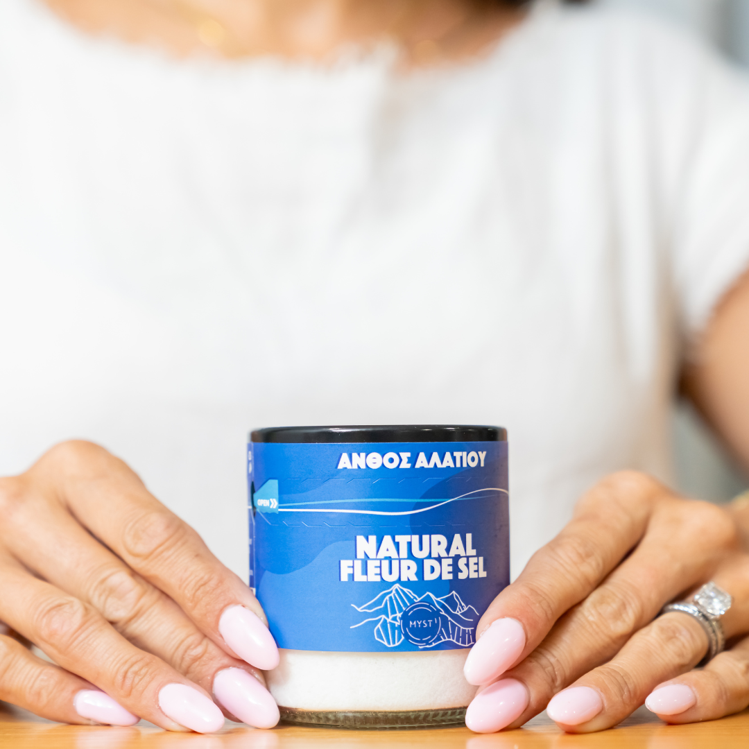 Person holding a container labeled 'Natural Fleur de Sel' with a blue label.
