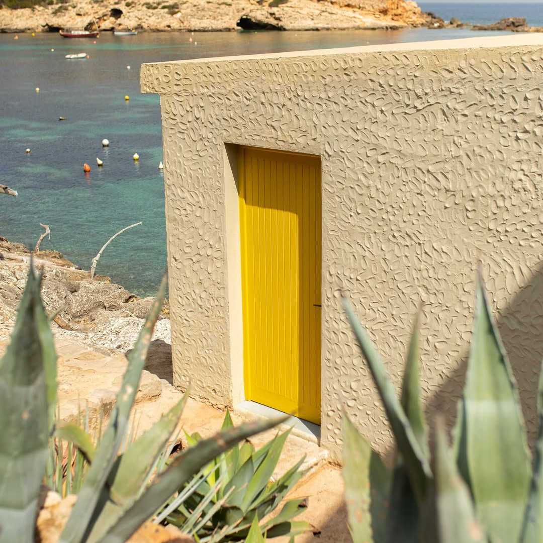 Beige building with a yellow door near a body of water