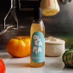 Bottle of Oleapia on a kitchen counter with pumpkins and a pot in the background