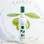 Bottle of olive oil with green leaves and 'Three Olives' branding on a light background