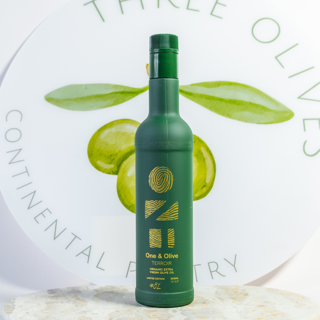 Green bottle of olive oil with leaves on a white background