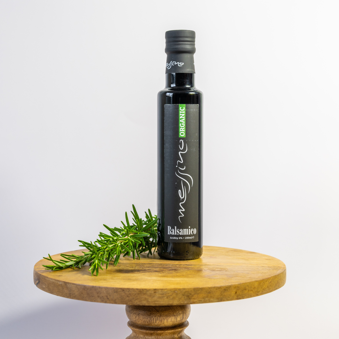 Bottle of organic balsamic vinegar on a wooden stand with a sprig of rosemary.