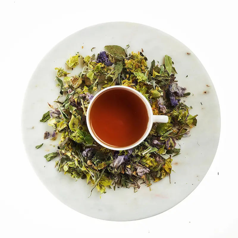 Tea cup with dried herbs on a white marble surface