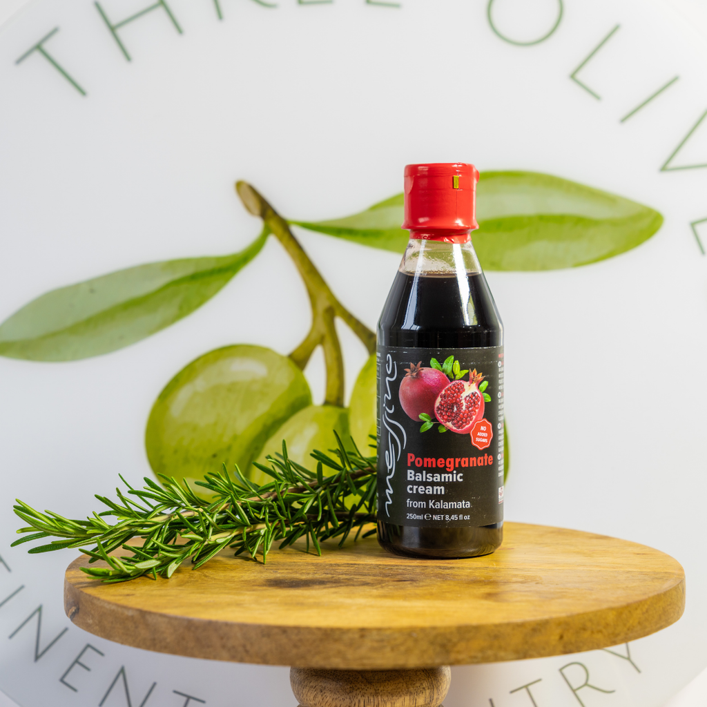 Bottle of Pomegranate Balsamic Cream on a wooden stand with green leaves in the background
