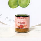 Pork rub spice mix container with green leaves on a white background