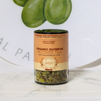 Jar of Organic Olympus Recover Tea with green leaves in the background