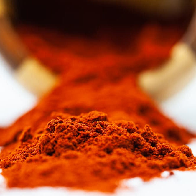 Red powder spilling out of a metallic container on a white background