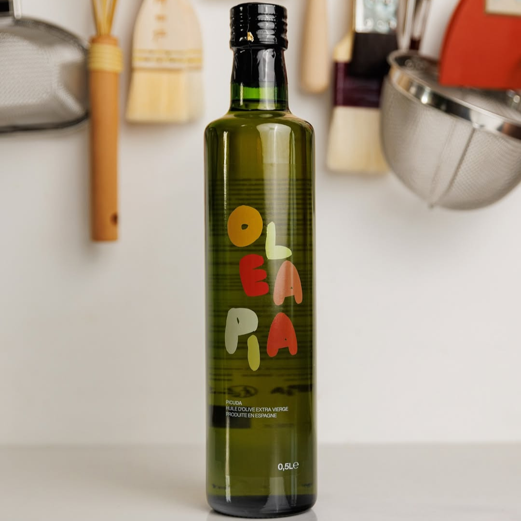 Bottle of OLA PA olive oil with kitchen utensils in the background