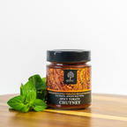 Jar of spicy tomato chutney with a label on a wooden surface