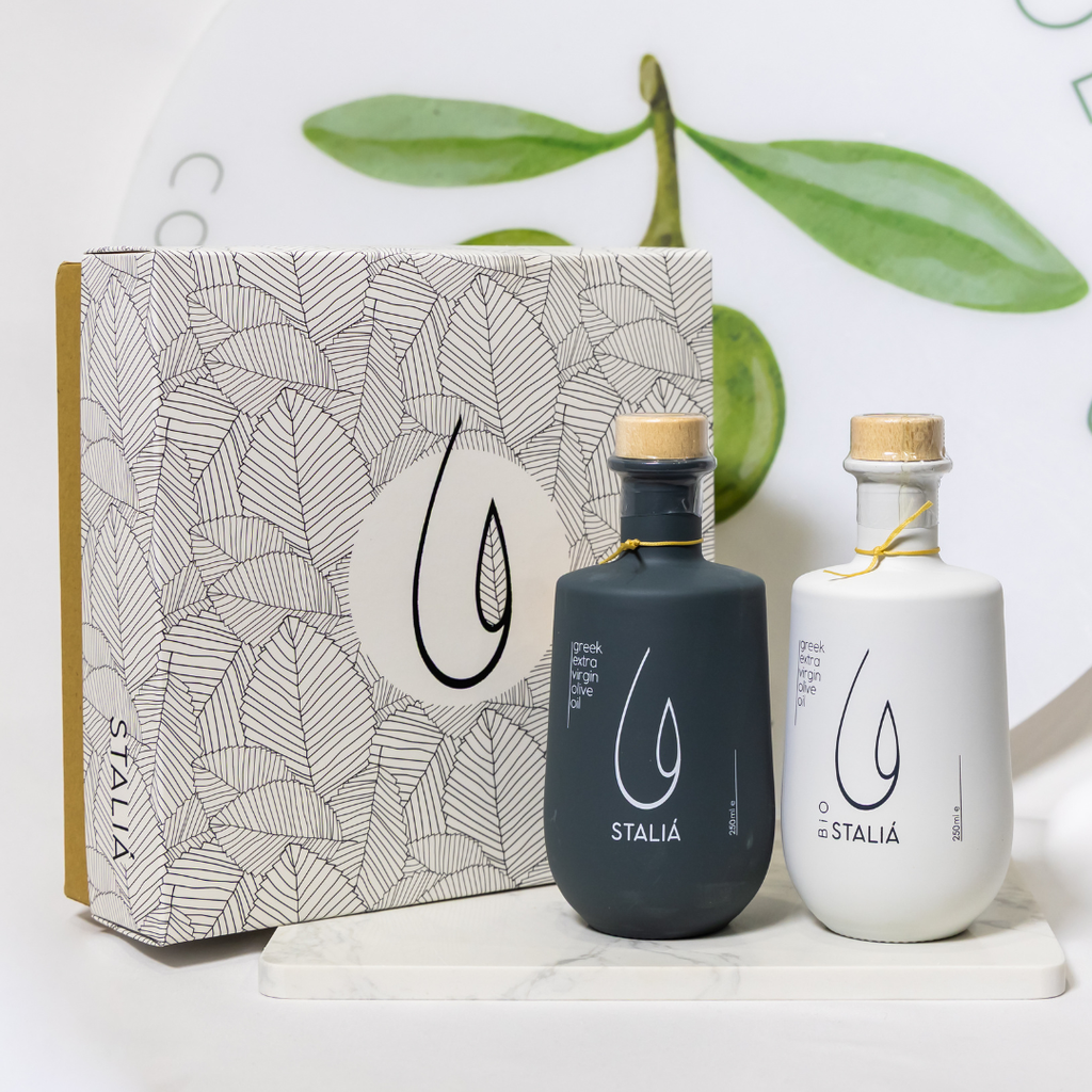 Two Staliá olive oil bottles with a decorative box on a light background