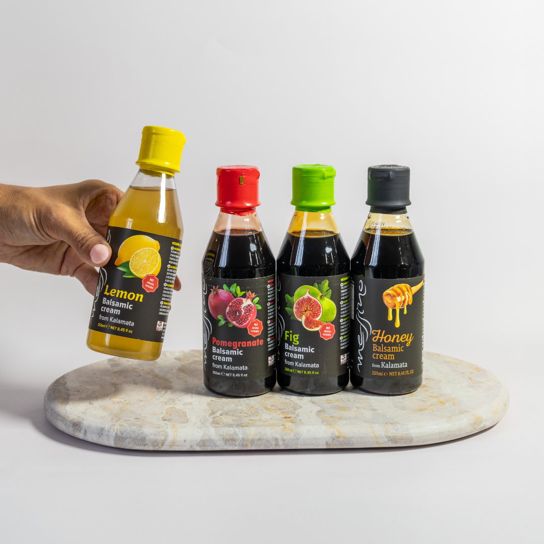 Four bottles of different flavors on a marble tray with a hand holding one bottle.