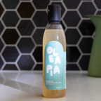 Bottle of Oleapia white balsamic vinegar on a kitchen counter with a hexagonal tile backsplash.