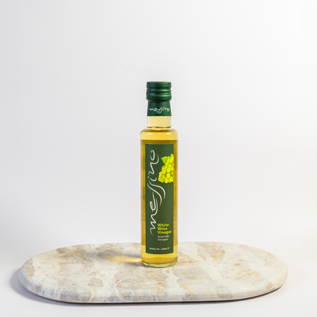 Bottle of Messina white wine vinegar on a marble coaster with a white background